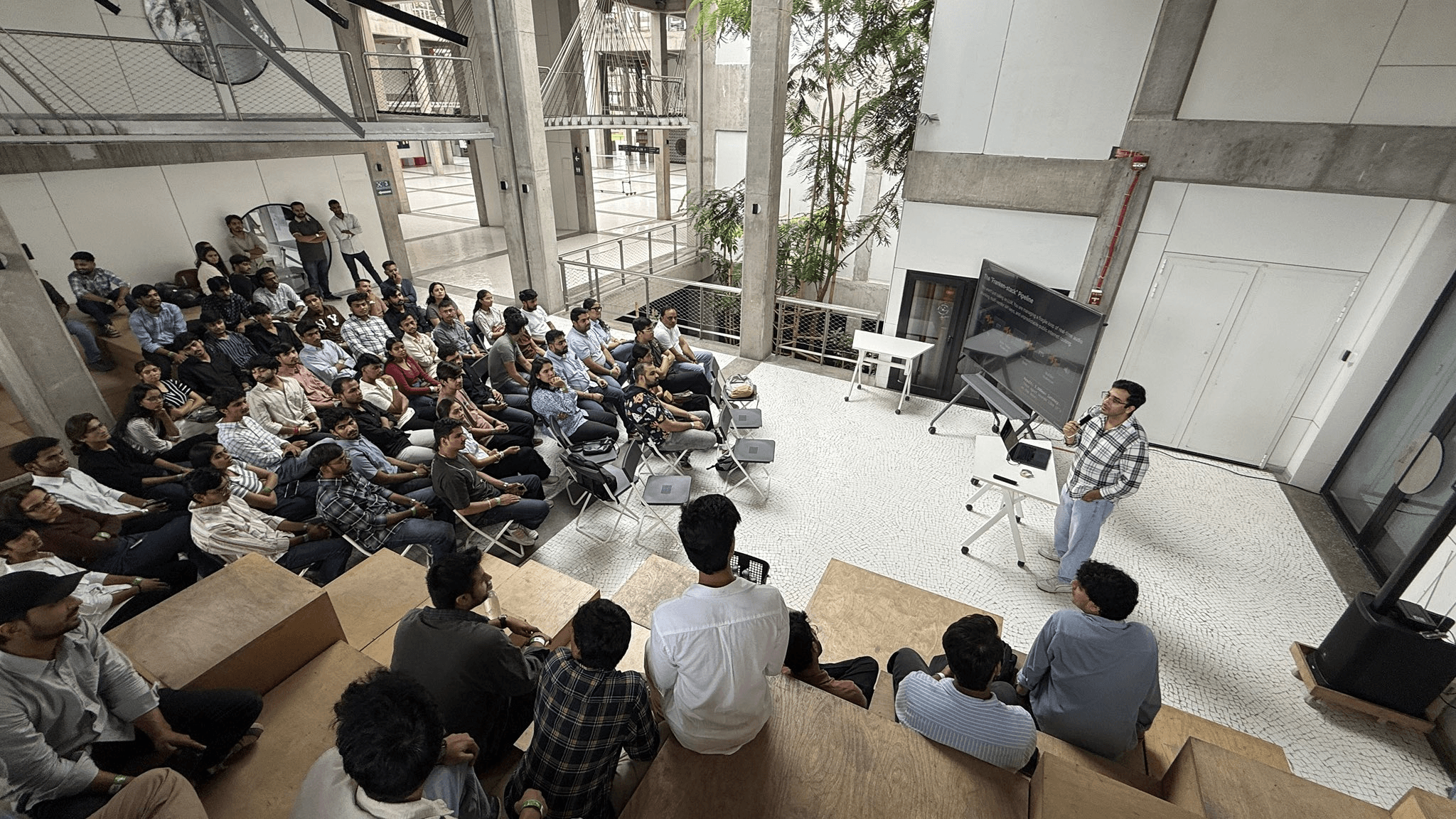 Akshay addressing a seated audience in an open tiered event space